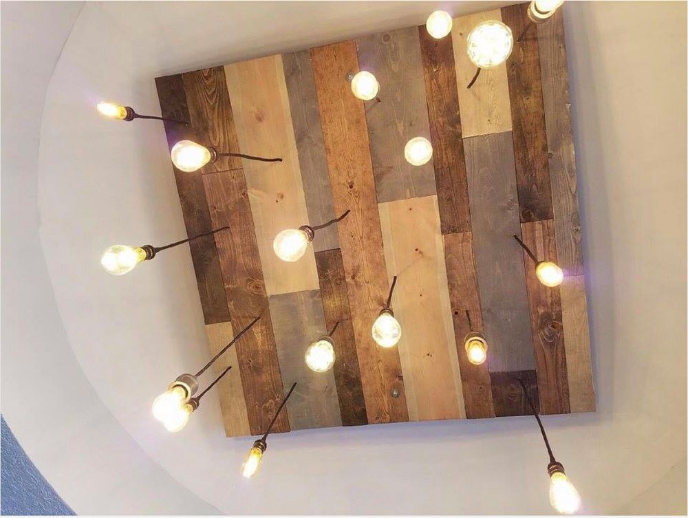 Wooden ceiling fixture with multiple hanging light bulbs, inside a room.