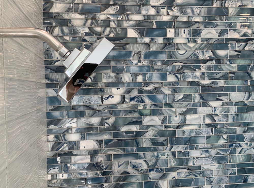 Silver shower head over blue and white patterned tile.