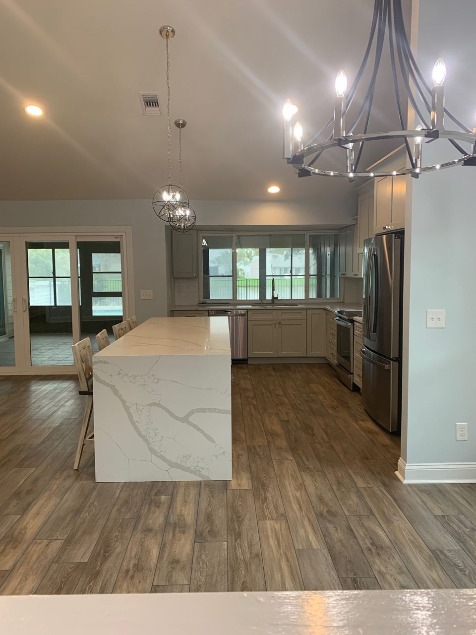 Modern kitchen with a large island, stainless steel appliances, and light gray cabinets.