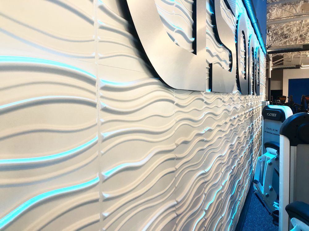 White wavy textured wall with blue accent lighting and large metal sign.