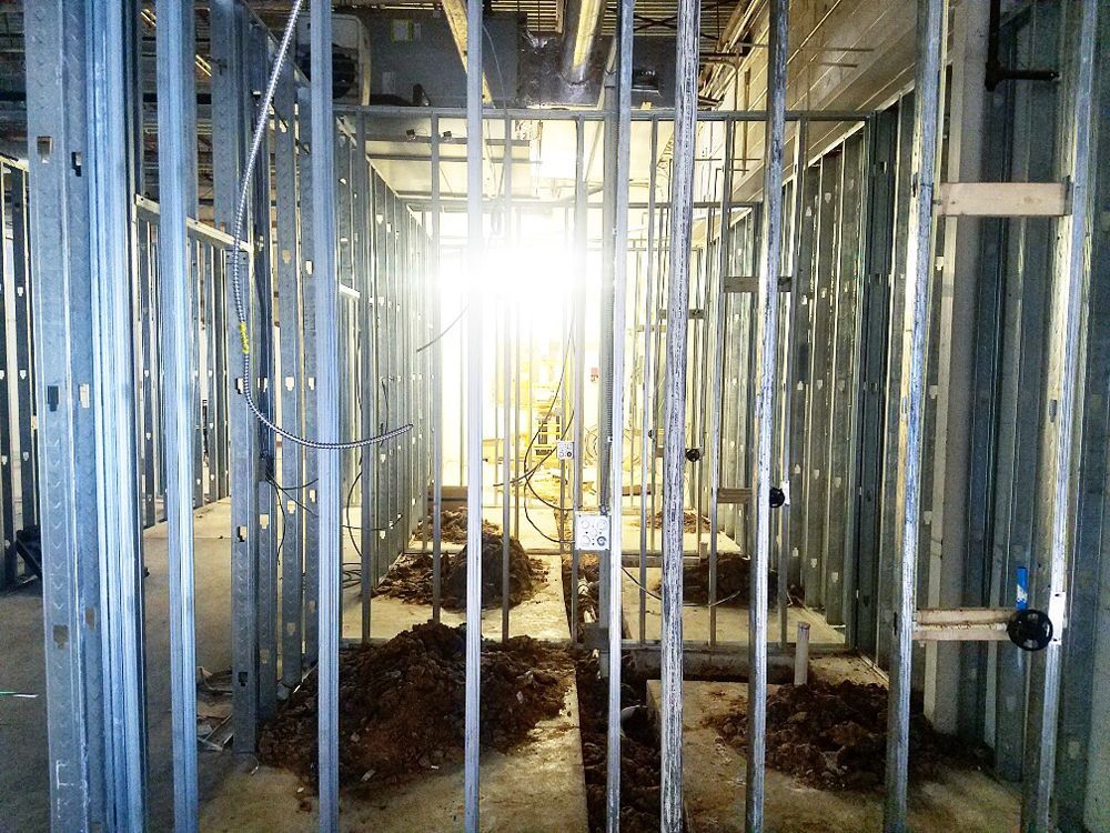 Metal framing for interior walls of a building under construction, with some debris on the floor.