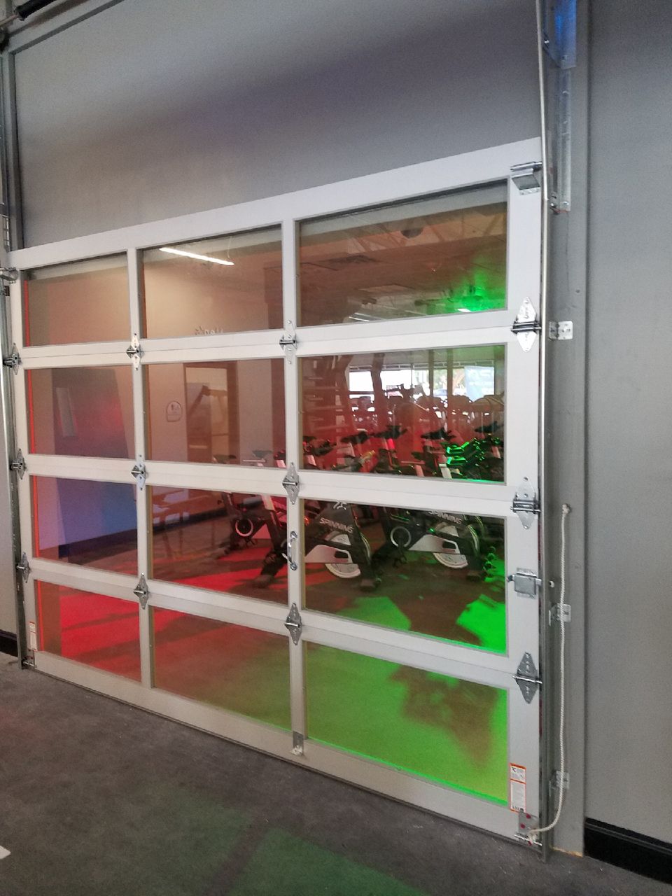 Glass garage door with red and green lighting illuminating the interior.