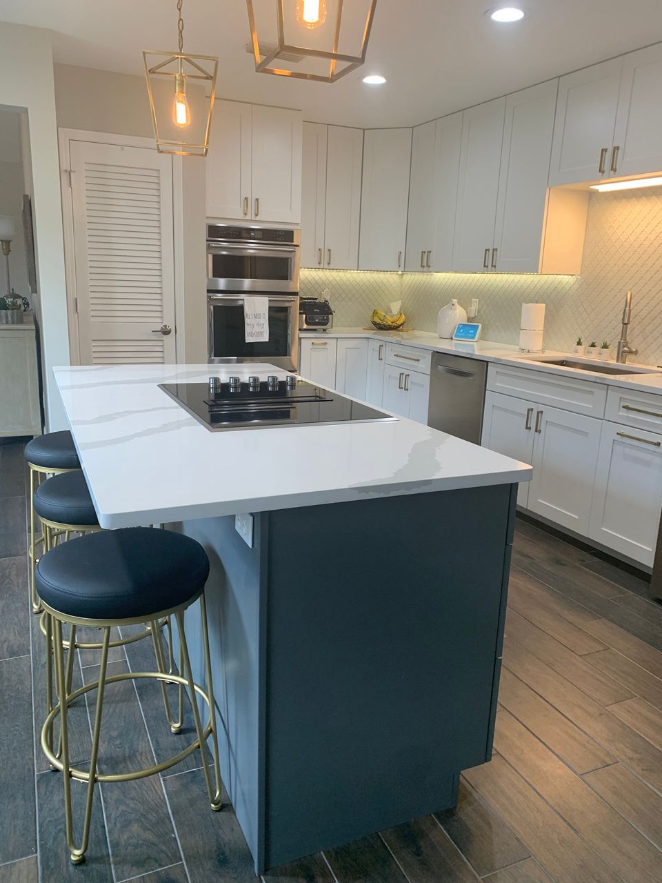 Modern kitchen with white cabinets, gray island, and gold accents.