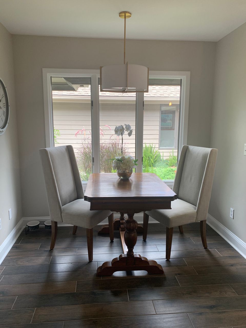 Dining room with a wooden table, two upholstered chairs, and a window with outdoor view.
