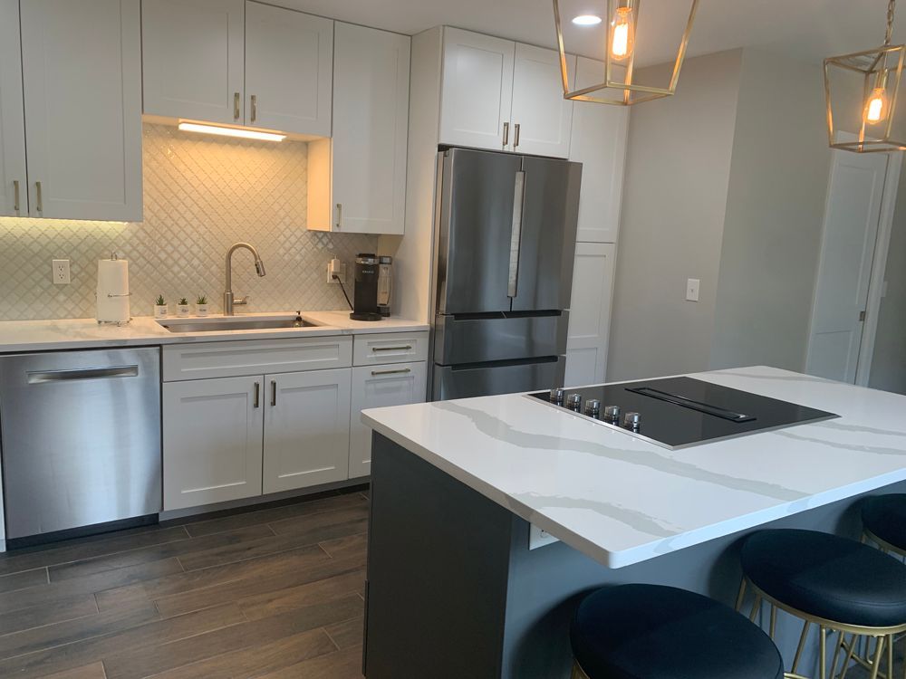 Modern kitchen with white cabinets, stainless steel appliances, and an island with a cooktop.
