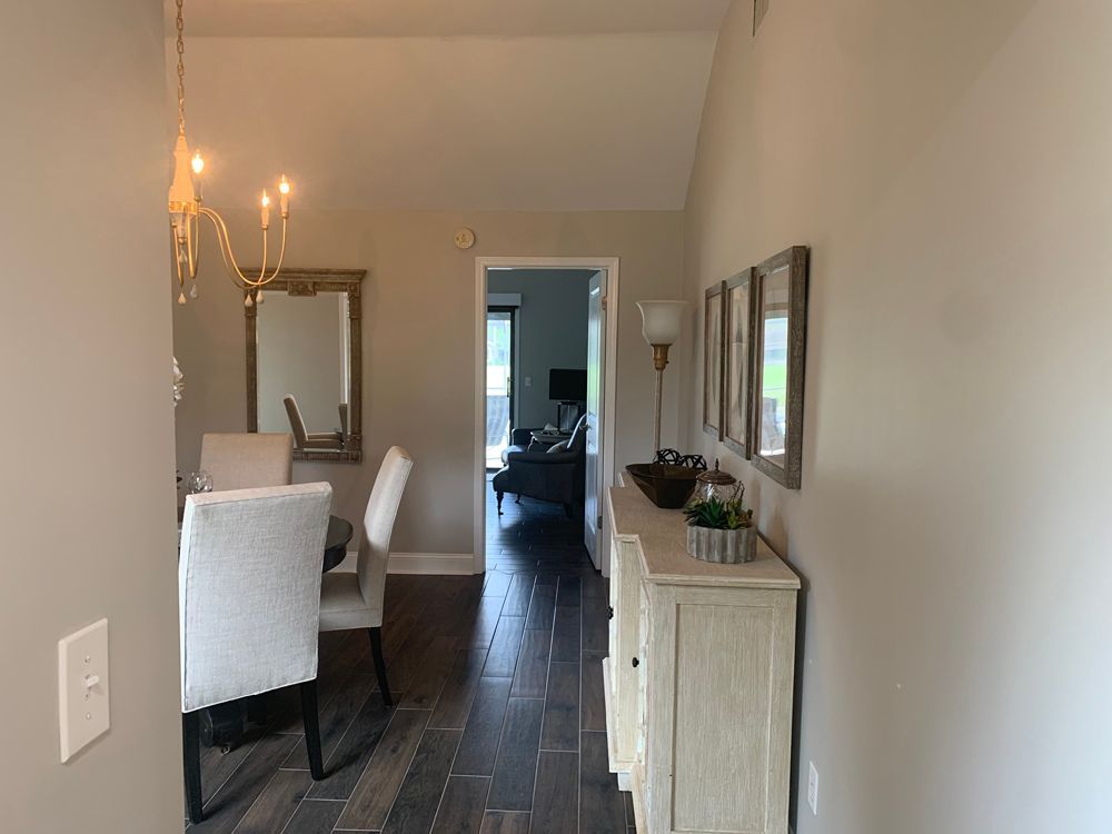 Hallway with wood floors leads to dining room and living room, featuring a sideboard and mirror.