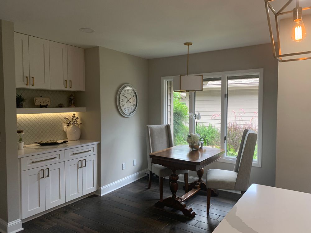 Dining room with a table, chairs, built-in cabinets, a window, and a clock on the wall.