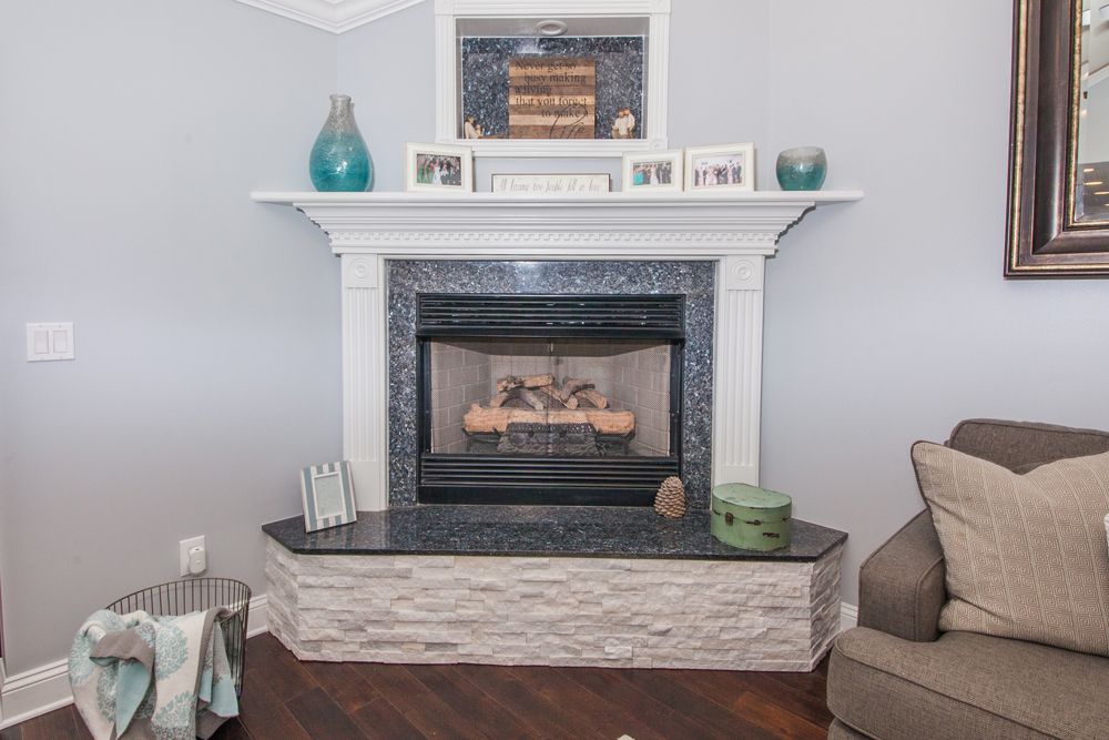 Fireplace with white mantel, blue-gray walls, wood floor, and decorative items.