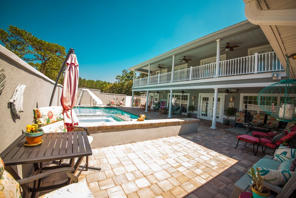 Two-story house with pool and patio. Exterior view with blue sky, gray, white, and brick tones.