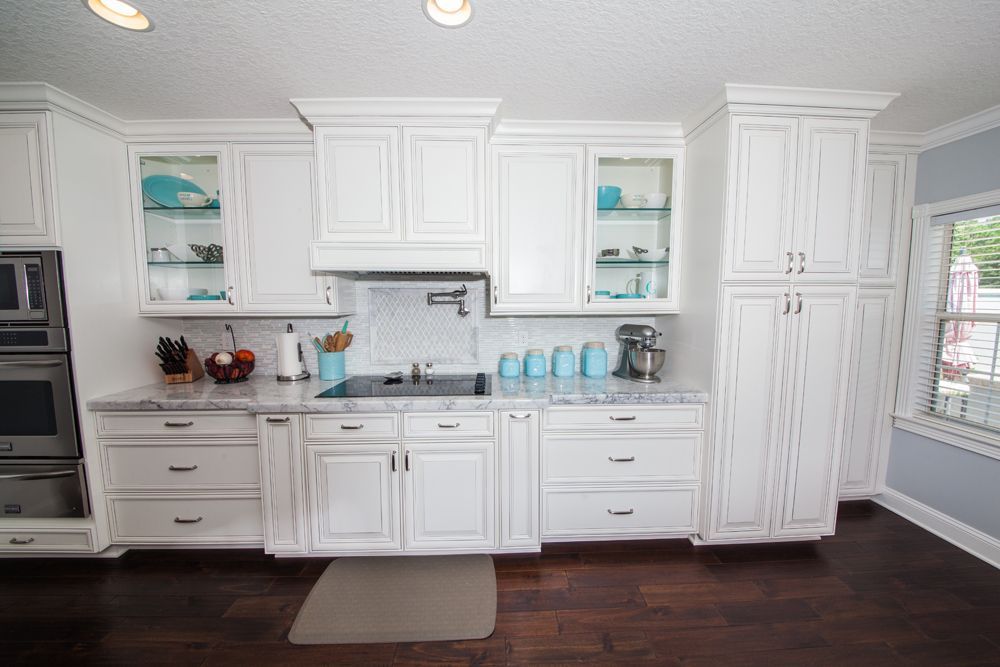 White kitchen with cabinets, dark wood floor, and light blue accents.