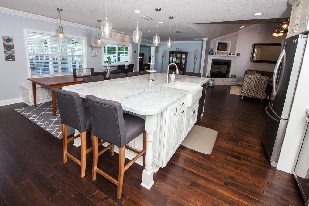 Spacious kitchen with island, dark wood floors, and a dining table.  A fireplace sits in the background.