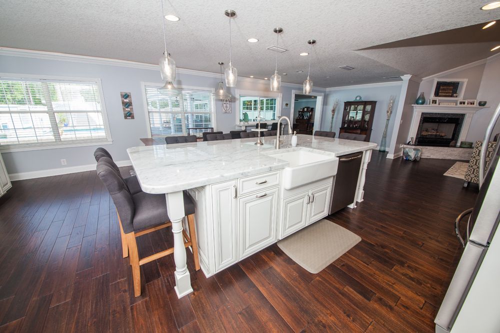 Spacious kitchen with a large island, white cabinets, and dark wood floors.
