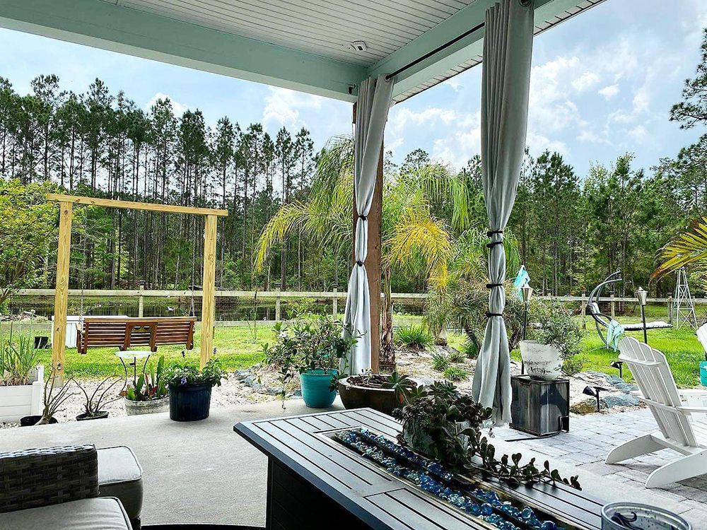 Patio overlooking a wooded landscape with a swing, fire pit, and various plants.