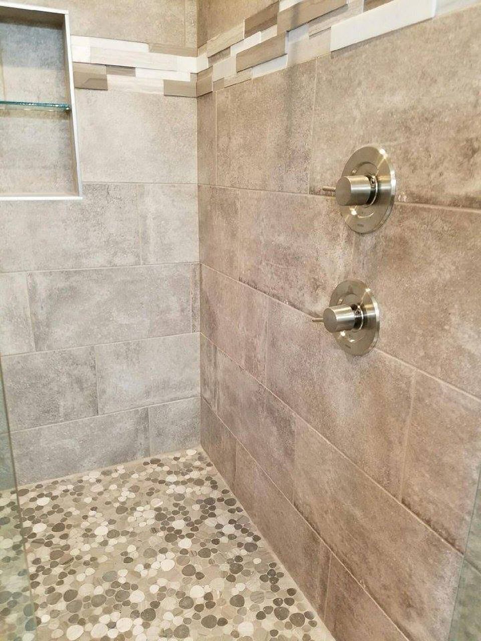 Shower with gray stone tile walls, pebble floor, and chrome shower controls.