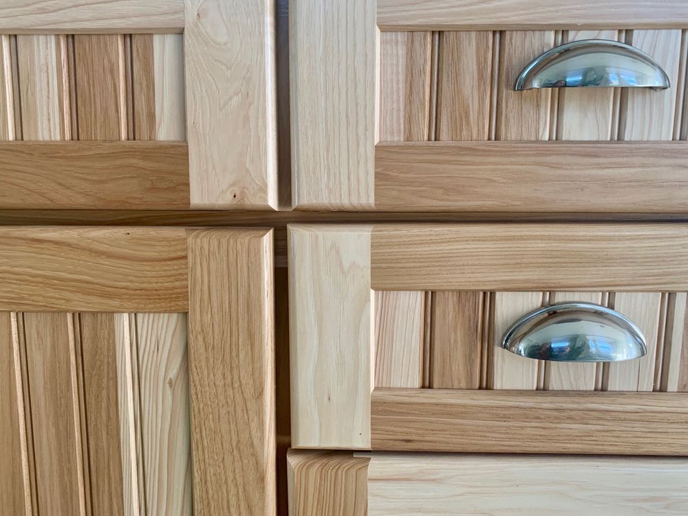 Wooden cabinet drawers with light and dark wood panels, chrome handles.