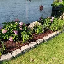 A garden with flowers and plants in front of a white brick wall.