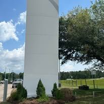 A large white tower is sitting in the middle of a field.