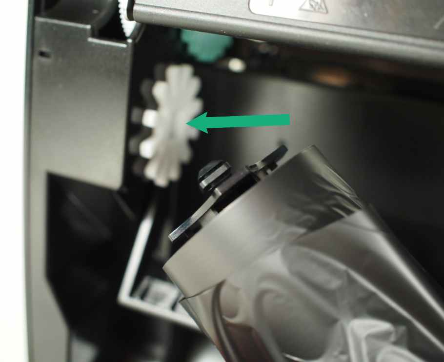 Install the unused roll of resin ribbon on the white gear of the printer