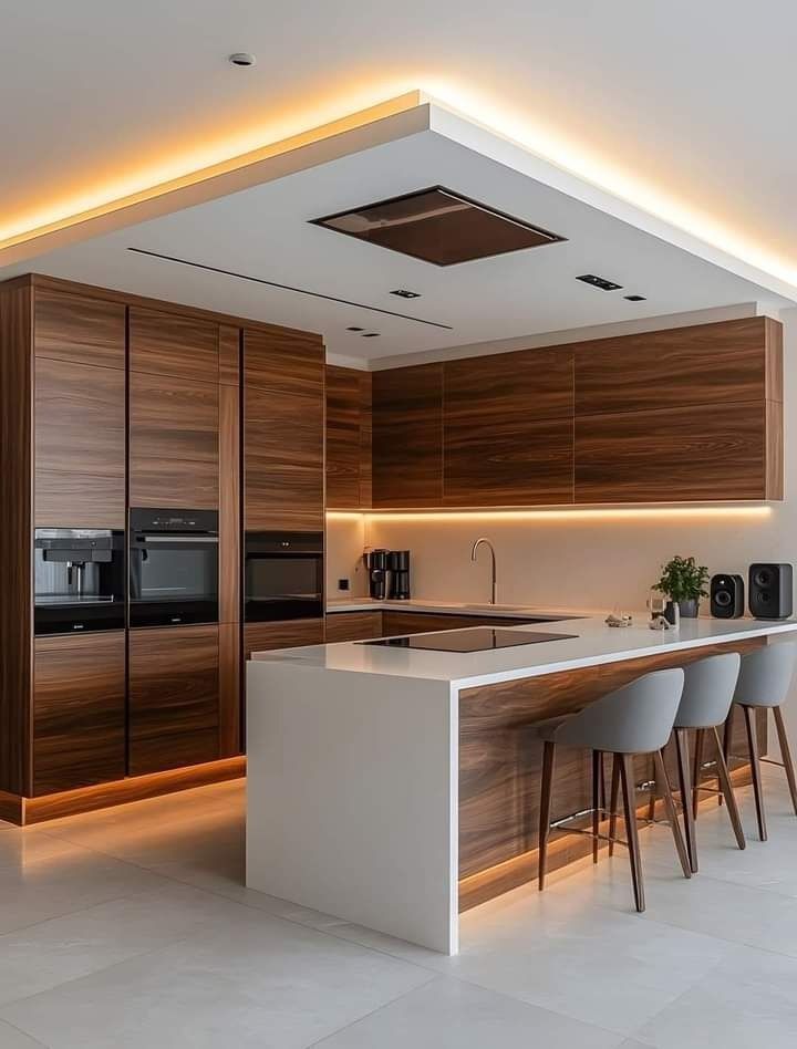 Cocina moderna con gabinetes de madera, isla blanca e iluminación cálida debajo de los gabinetes.