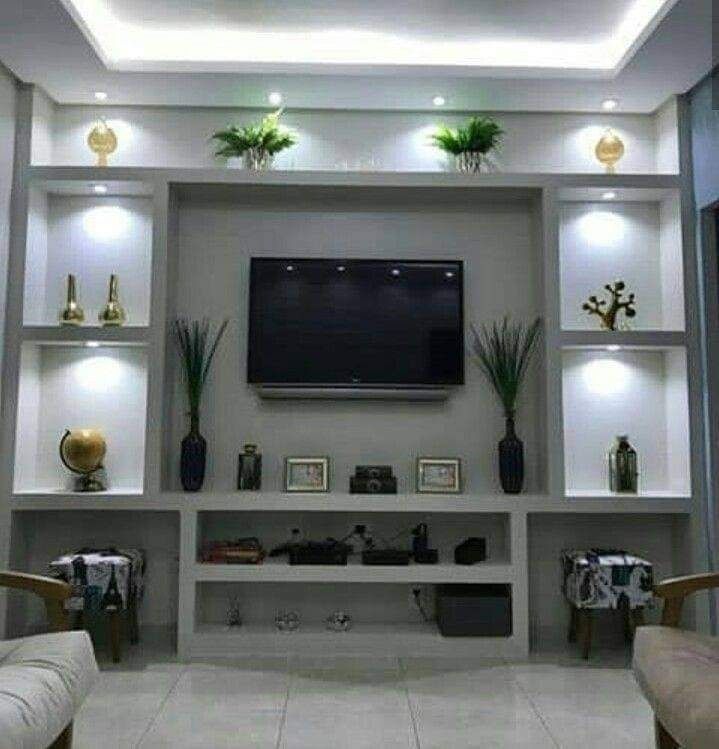 Mueble modular moderno para salón con TV, estantes, plantas y detalles decorativos en tonos neutros.