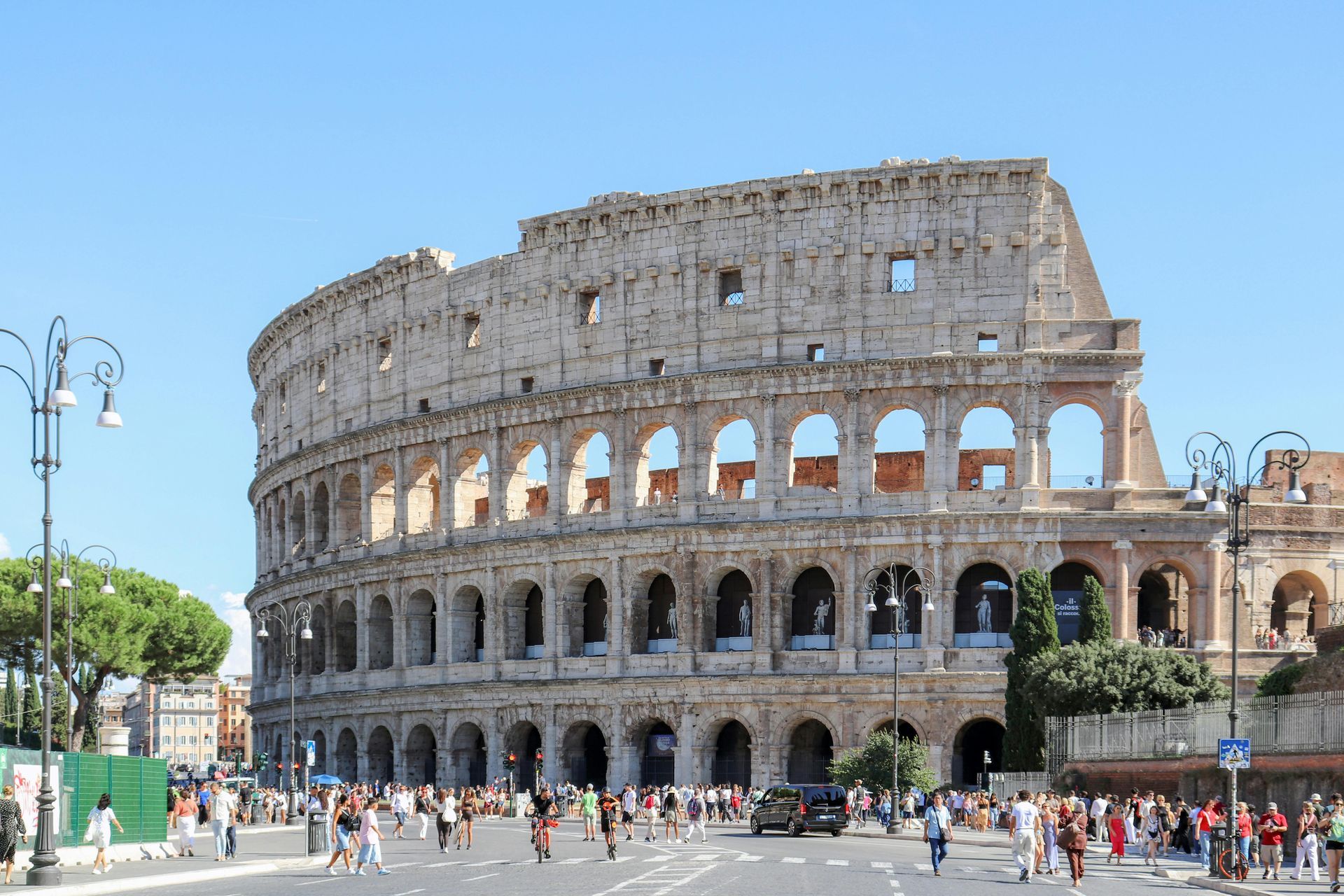 El Coliseo de Roma con multitudes de turistas bajo un cielo azul despejado.