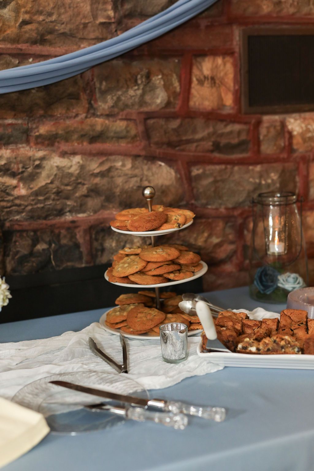 A table with three plates of cookies on it and a brick wall in the background.