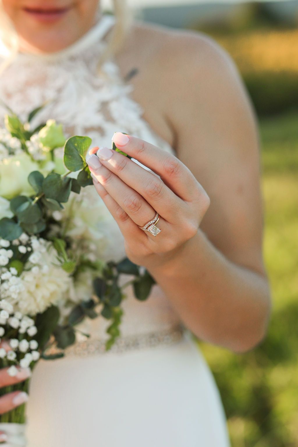 The bride is wearing a wedding ring and holding a bouquet of flowers.