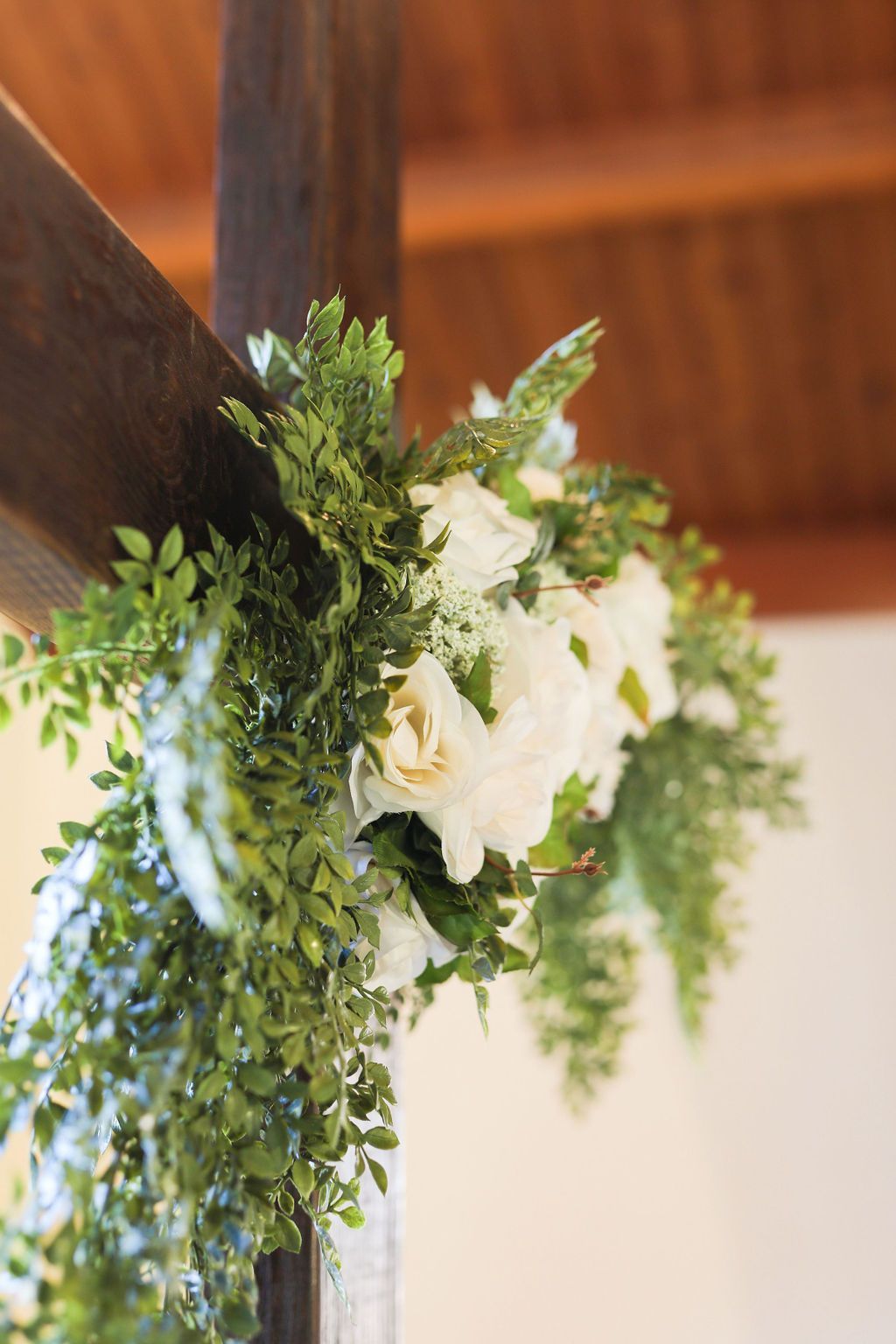 A wooden cross decorated with white flowers and greenery.