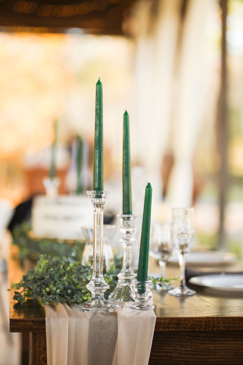 A wooden table with candles and glasses on it.