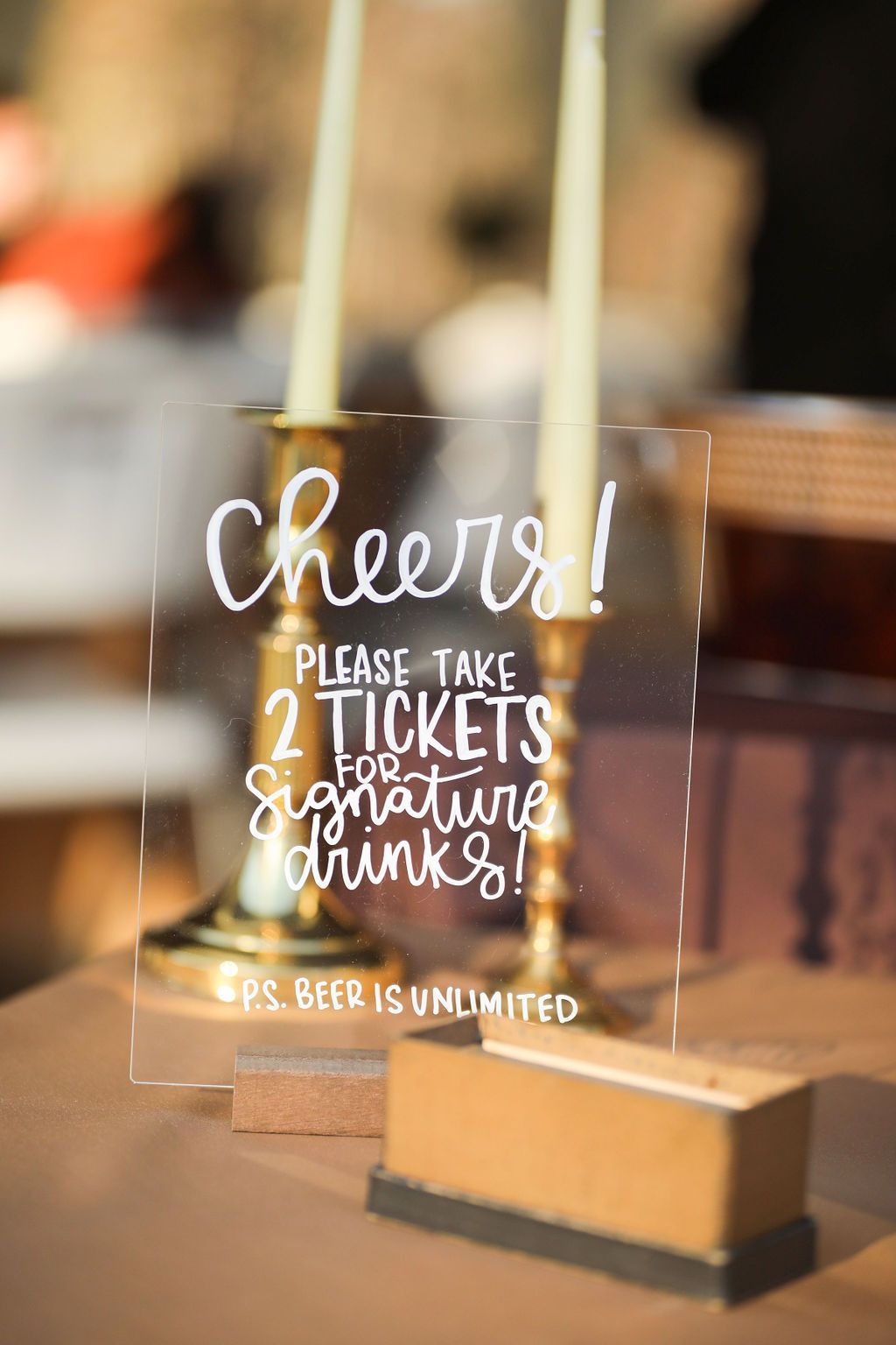 A glass sign that says `` cheers ! please take 2 tickets for signature drinks ! ''