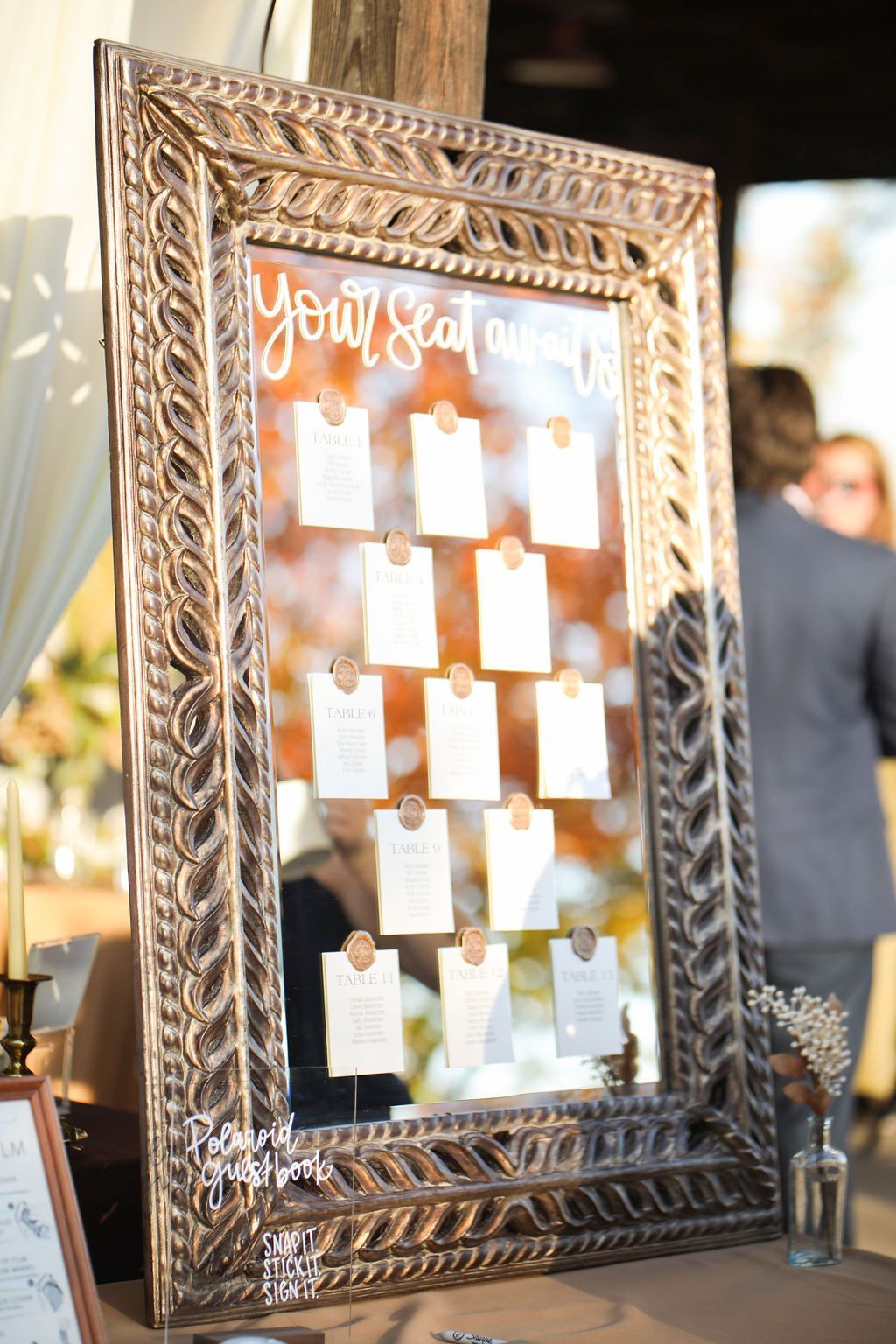 A large mirror with a seating chart on it is sitting on a table.