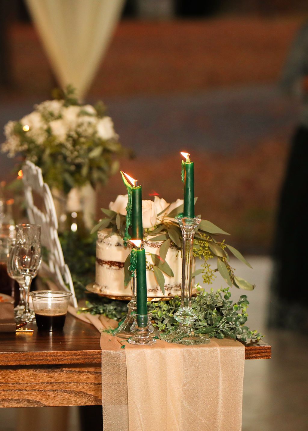 A table with candles , flowers and a cake on it.