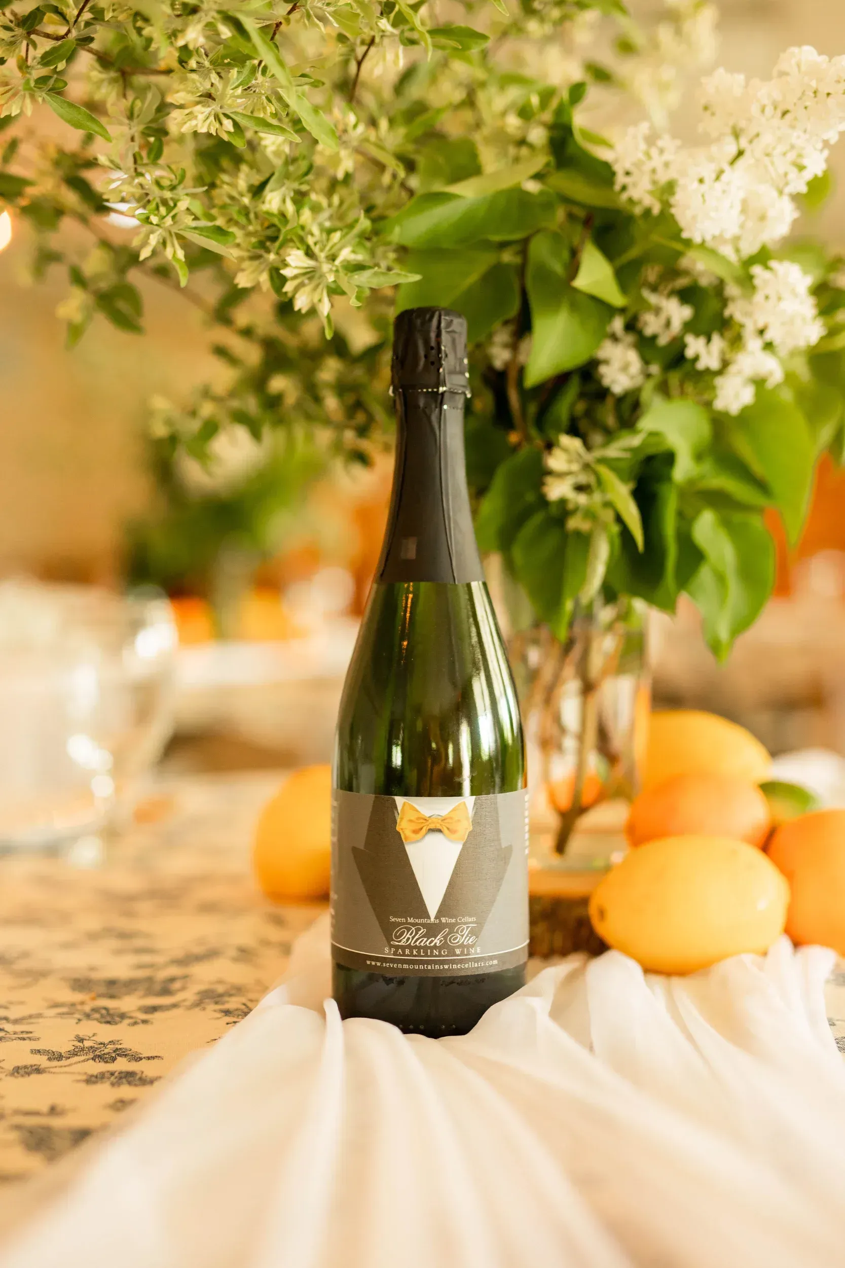 A bottle of champagne is sitting on a table next to a vase of flowers.