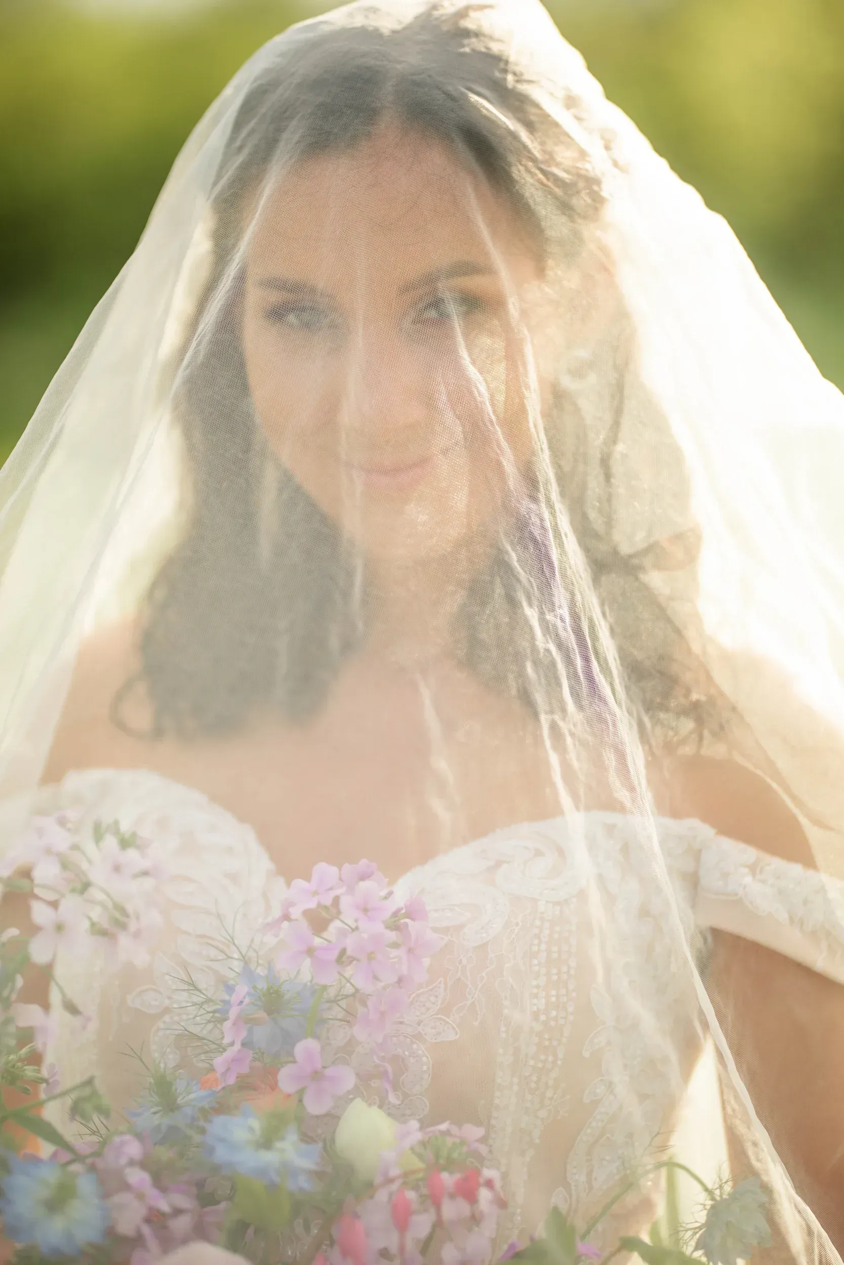 The bride is wearing a veil and holding a bouquet of flowers.