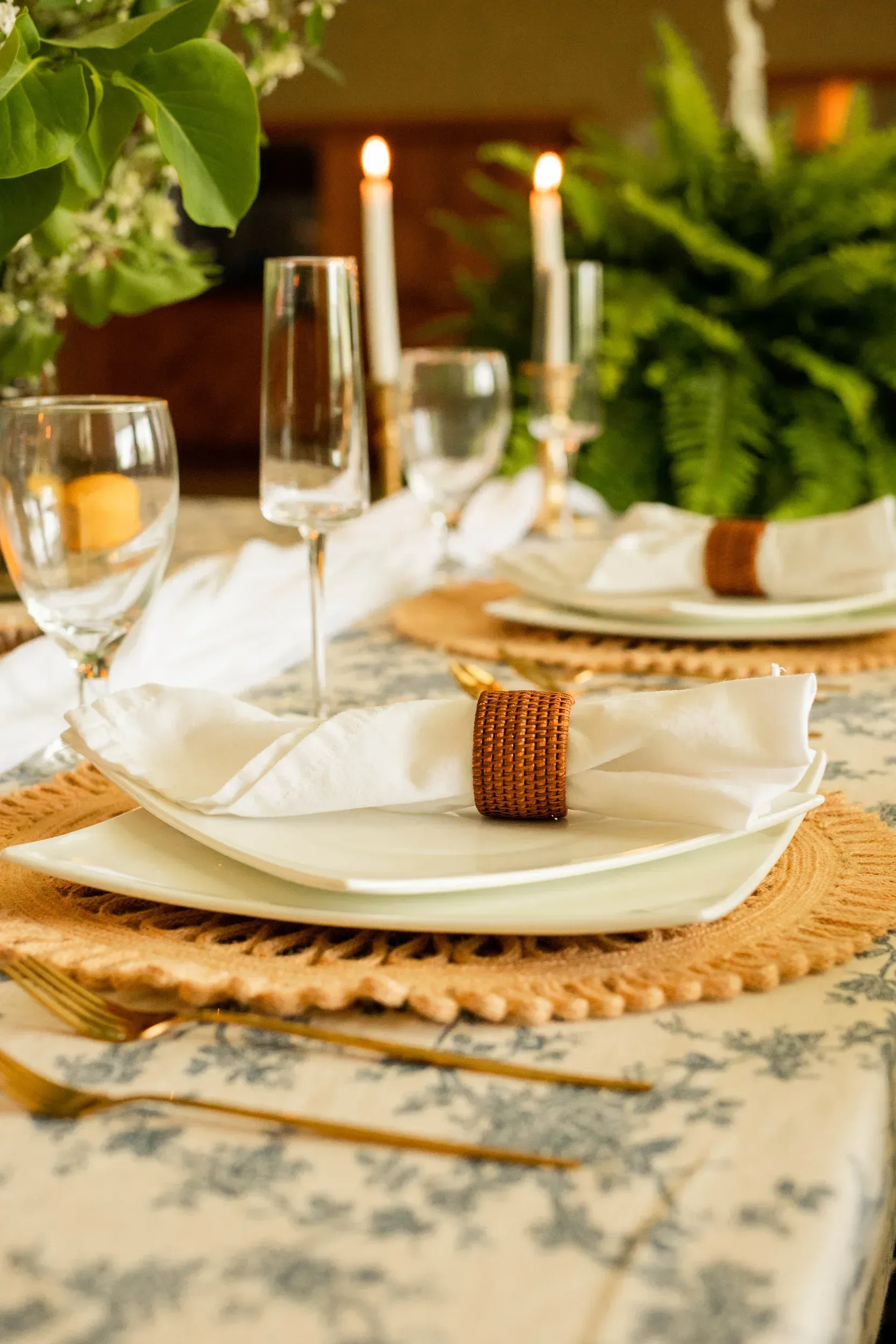 A table set for a dinner party with plates , candles , glasses and napkins.