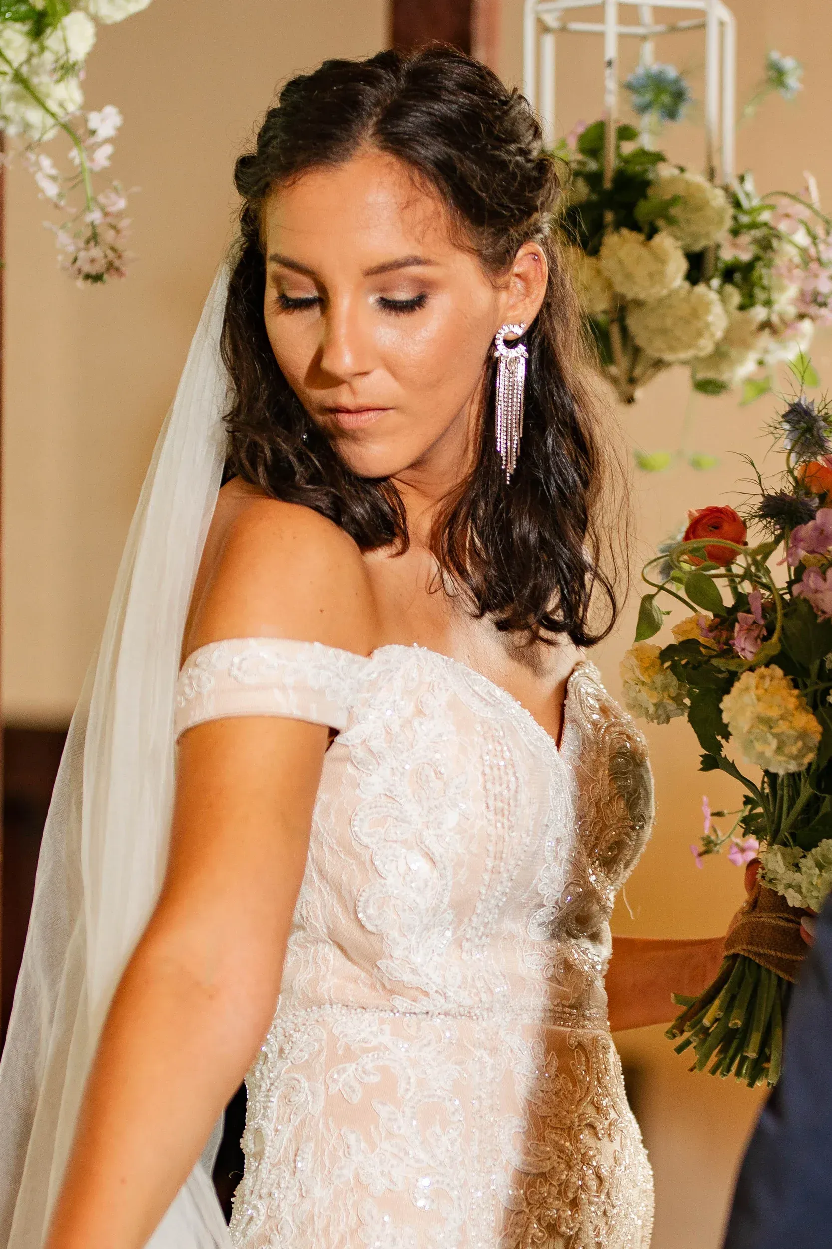 A woman in a wedding dress and veil is standing in front of a bouquet of flowers.