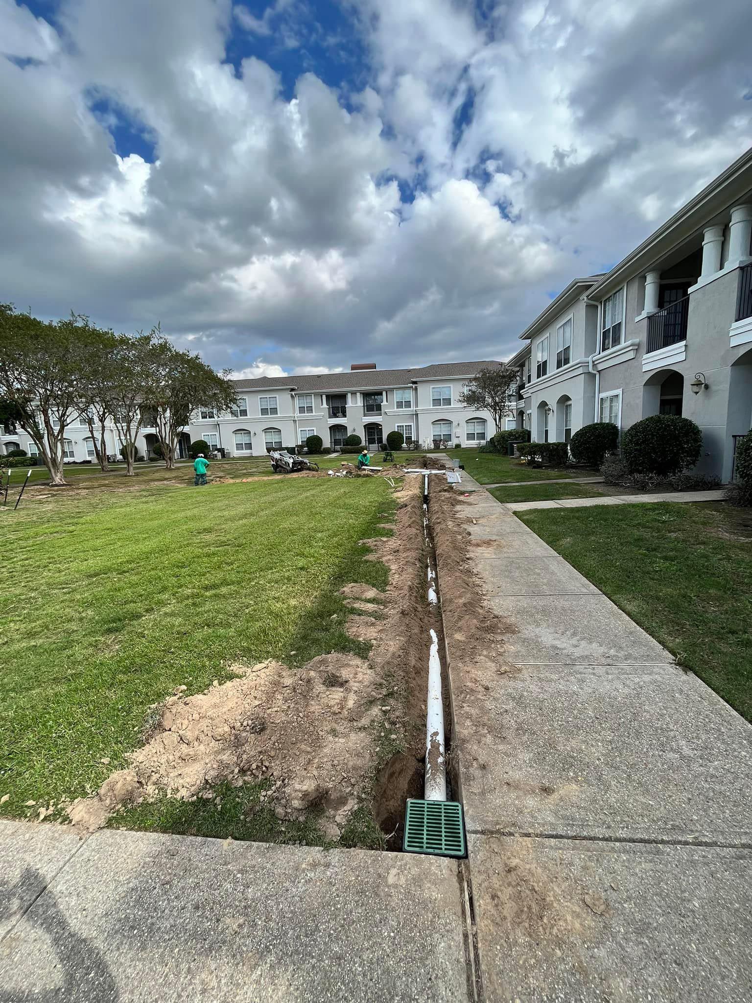 A sidewalk leading to a building with a grassy field in front of it.