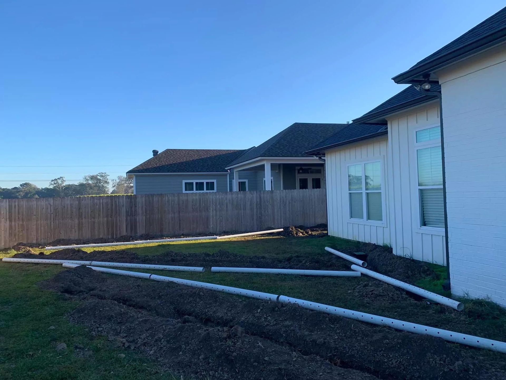 A white house with a wooden fence in the backyard.