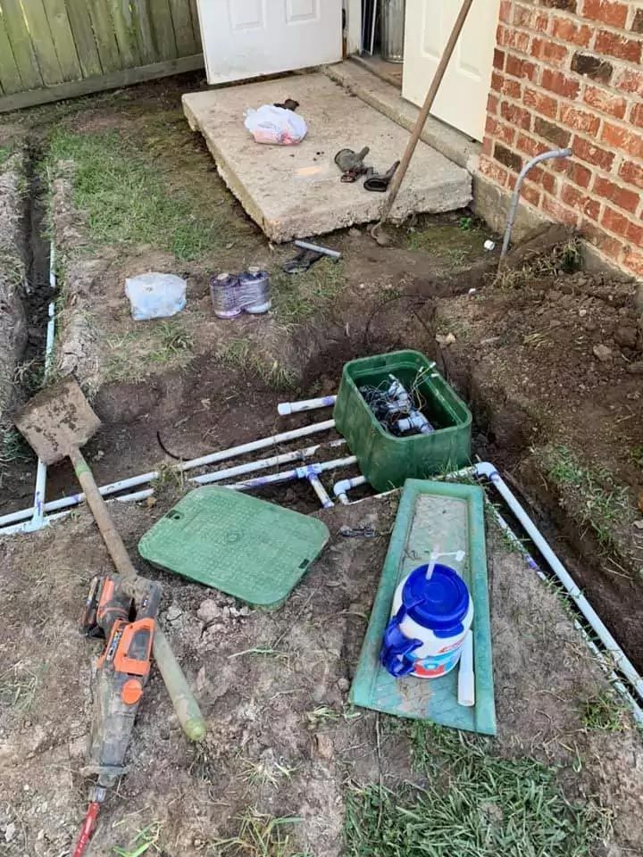 A sprinkler system is being installed in the backyard of a house.
