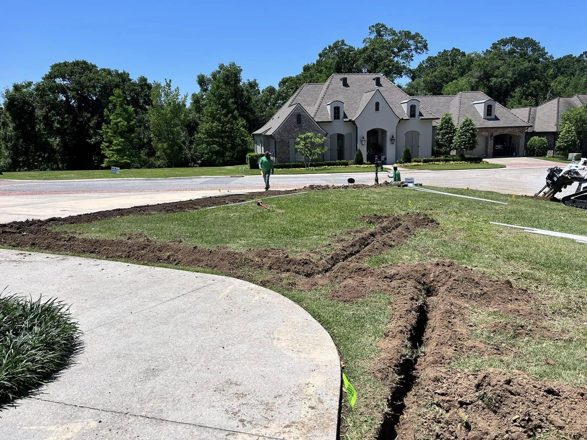 A man in a green shirt is standing in front of a large house.