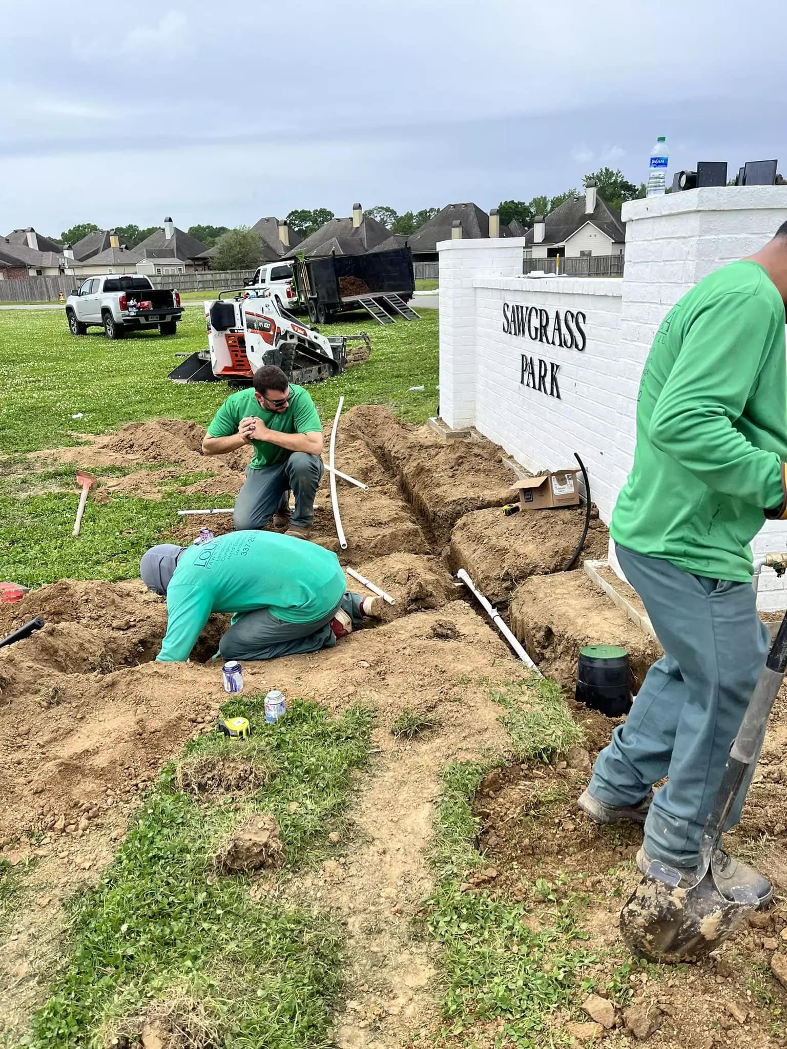 A group of men are digging in the dirt in a field.