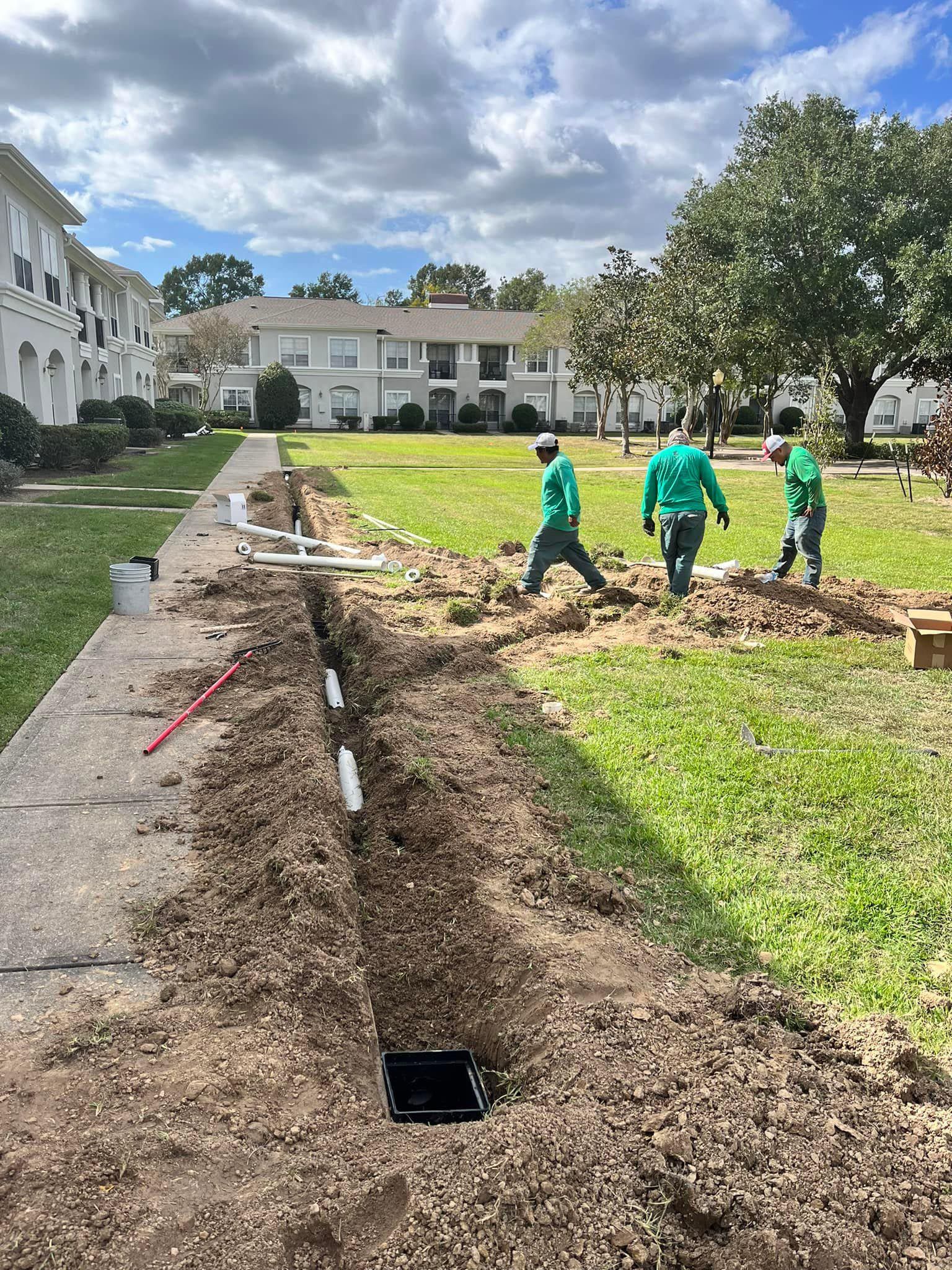 A group of men are digging a hole in the ground in front of a building.
