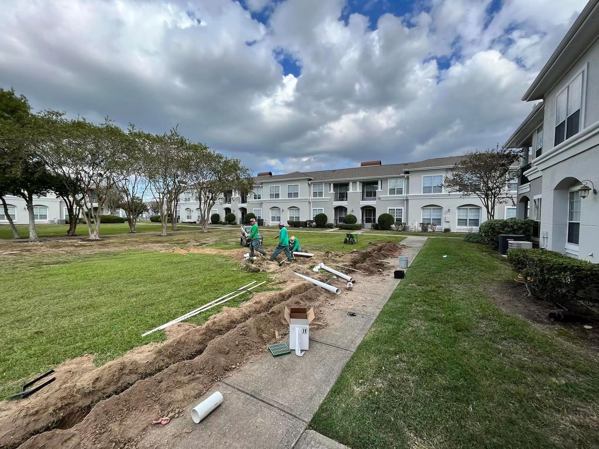 A group of people are working on a sidewalk in front of a building.