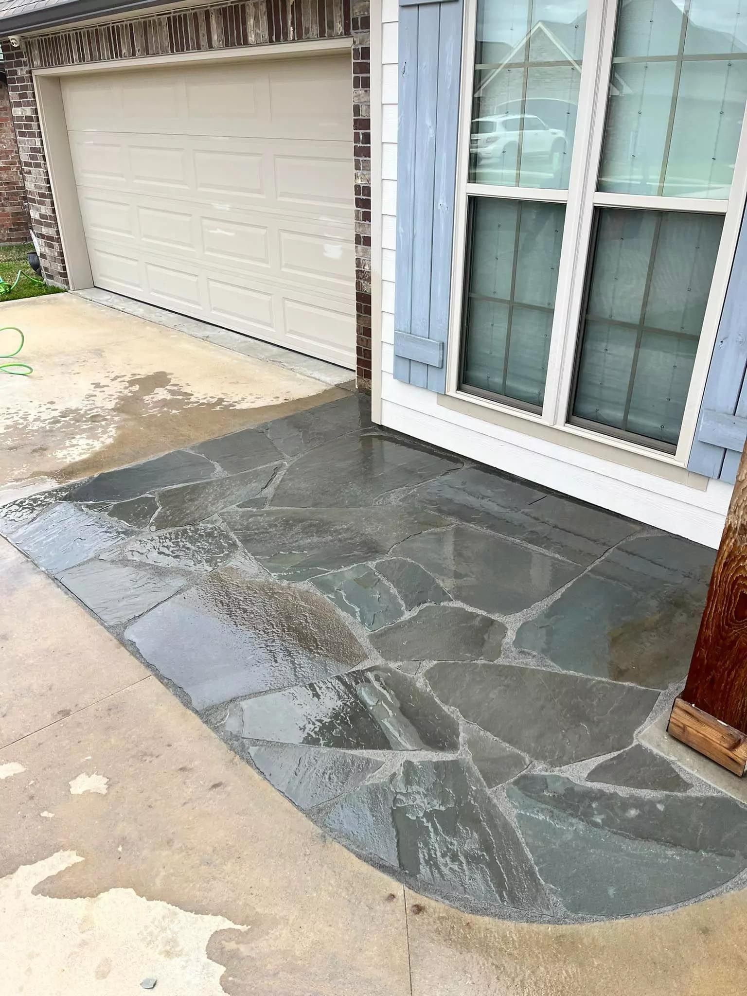 A stone walkway in front of a house next to a garage door.