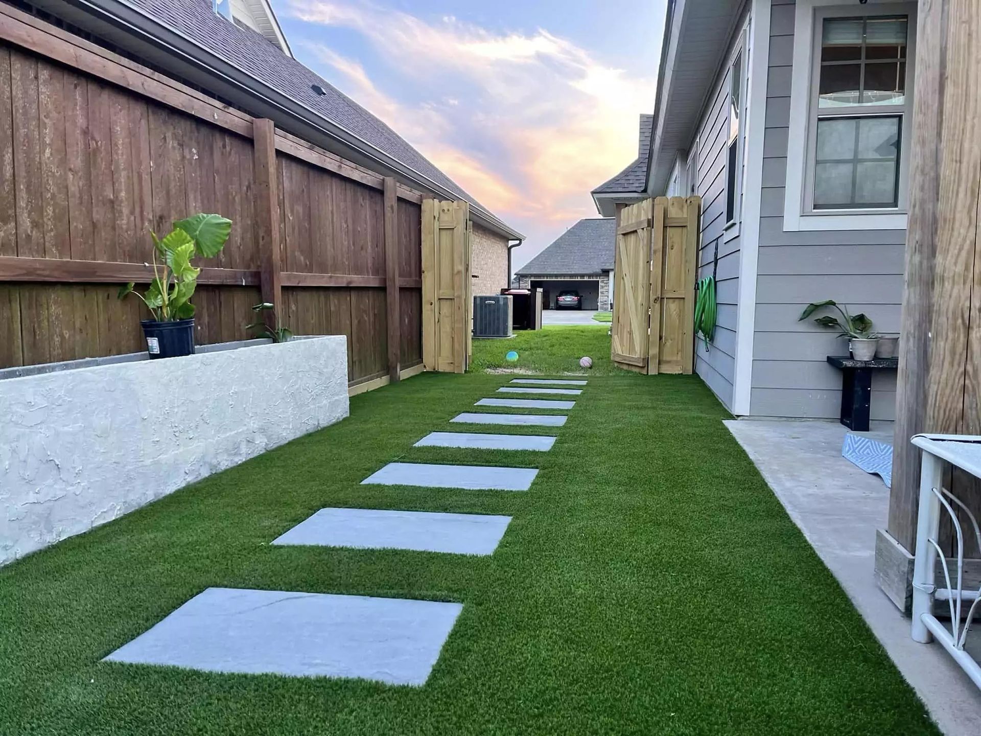 A walkway leading to a house with a wooden fence.