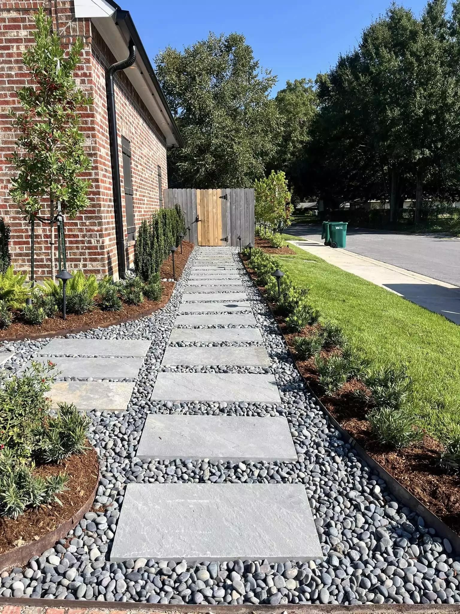 A stone walkway leading to a house with a wooden gate.