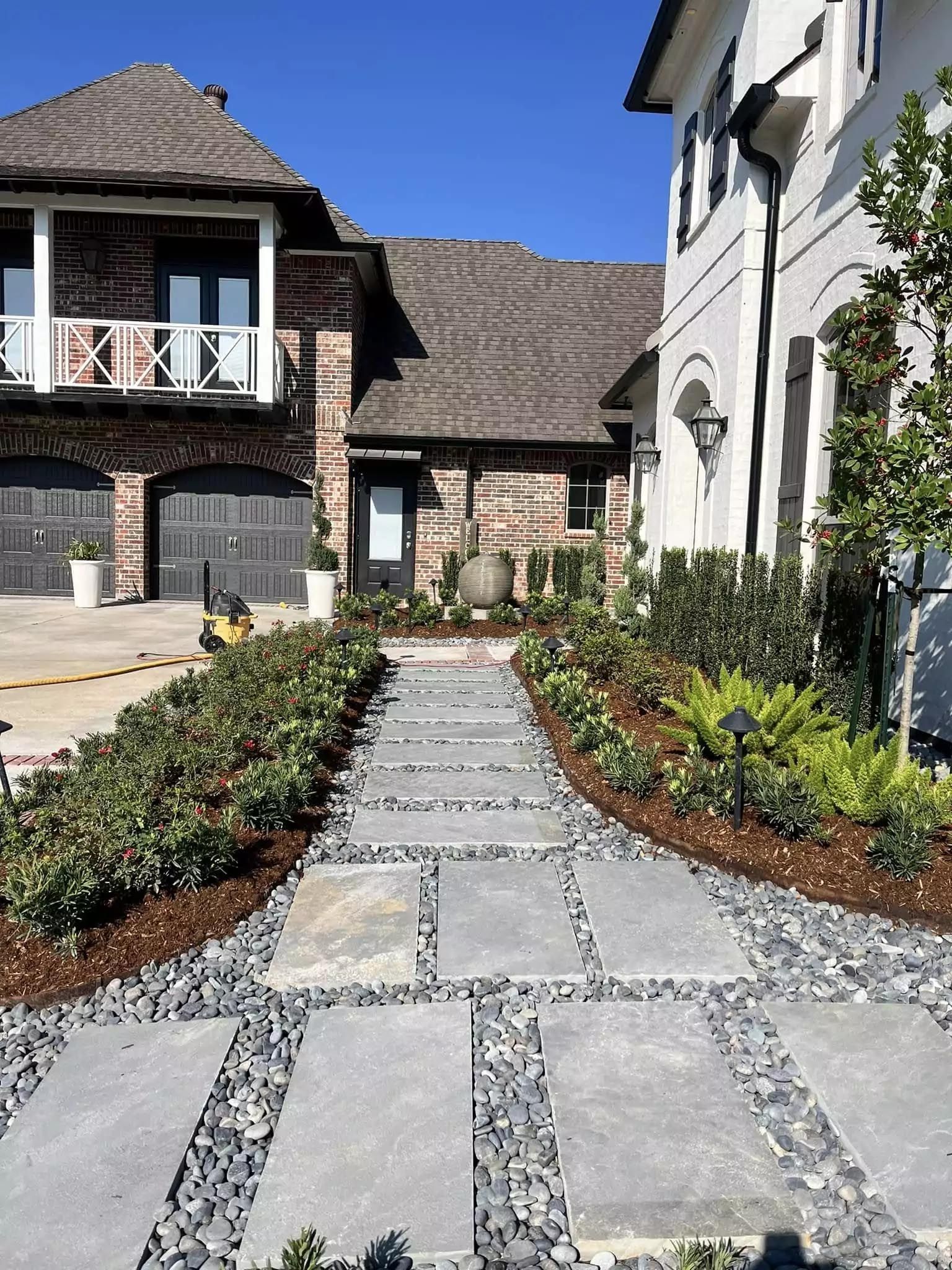 A stone walkway leading to a large house with a large garage.