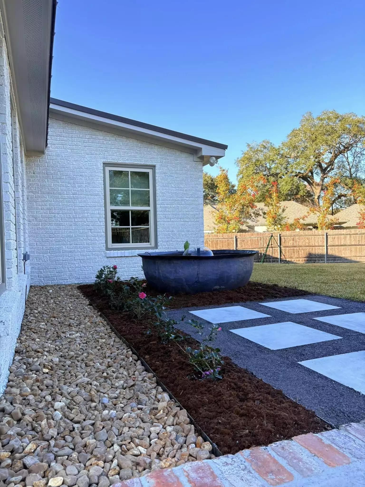 A white brick house with a fire pit in the backyard.