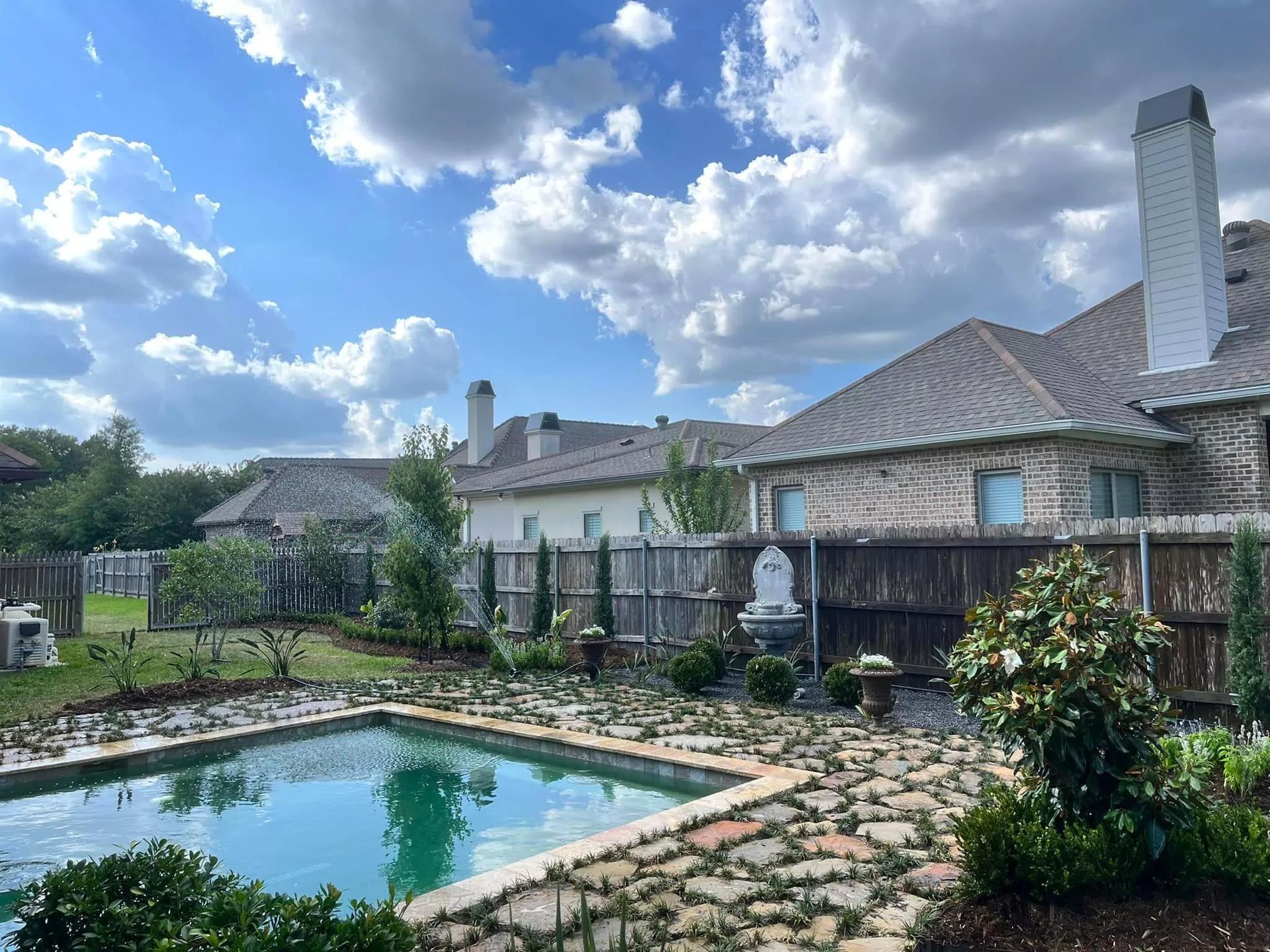There is a large swimming pool in the backyard of a house.