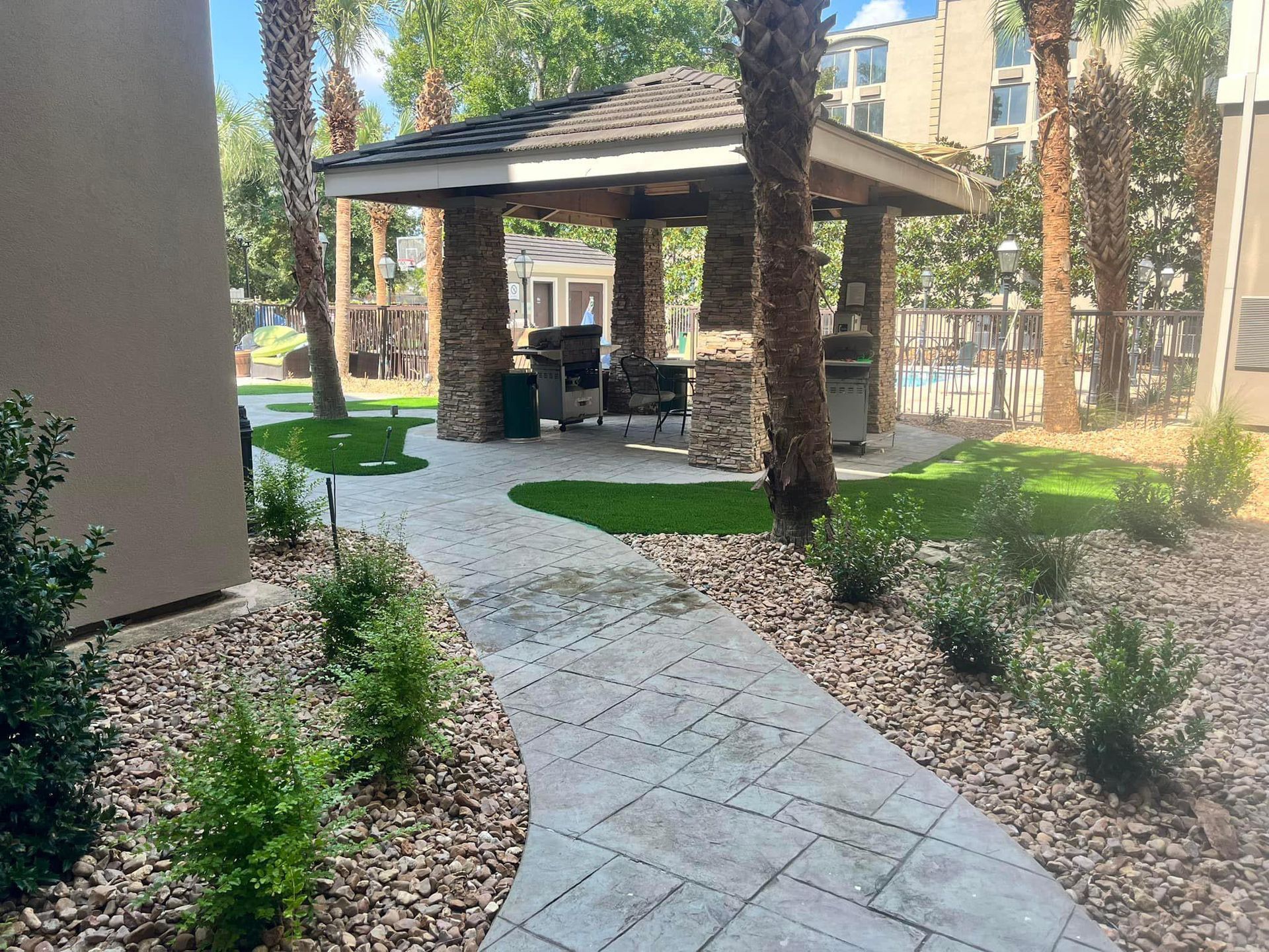 A walkway leading to a gazebo in a park with palm trees.